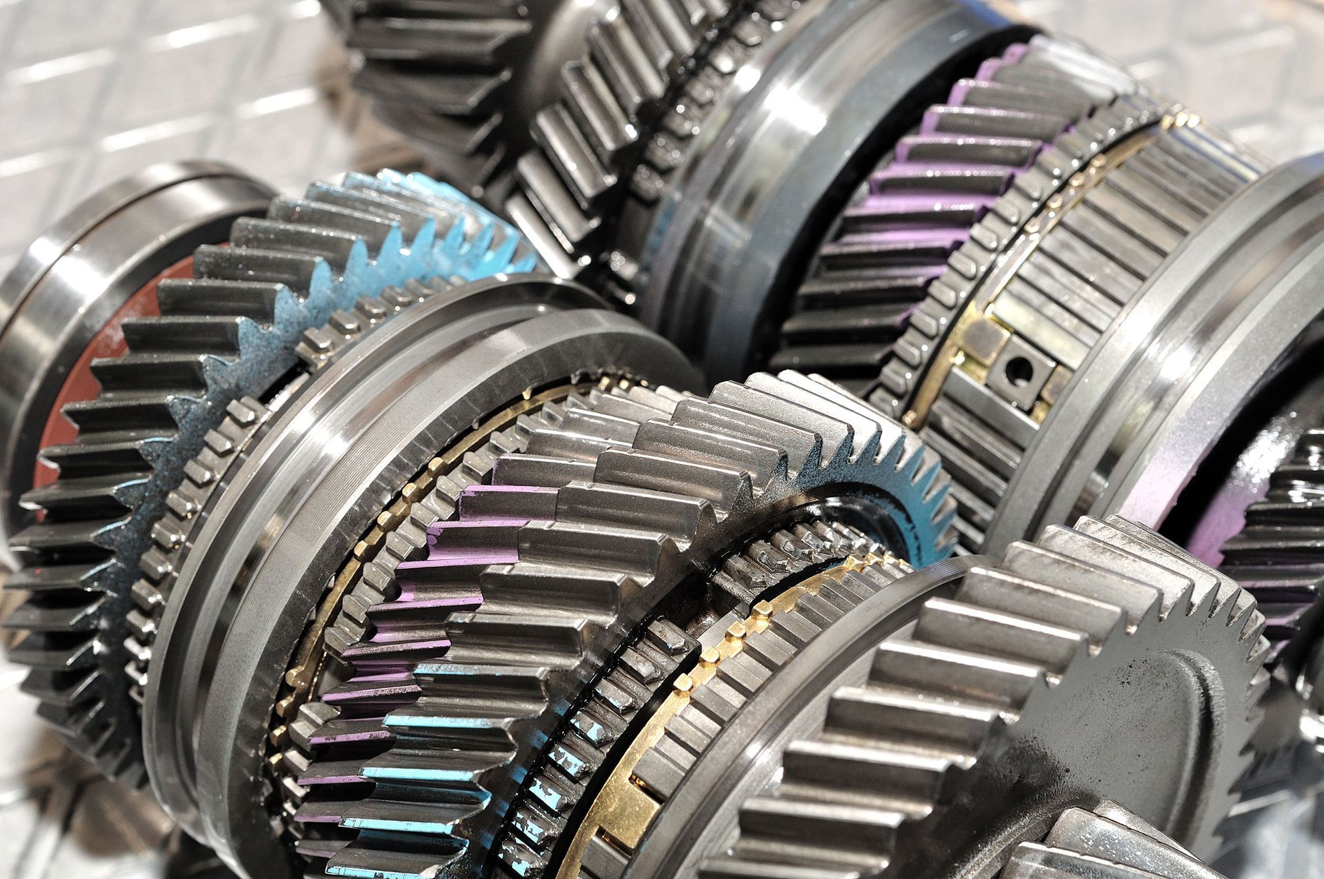 Close-up of stacked metallic gears and transmission parts with silver, purple, and blue accents