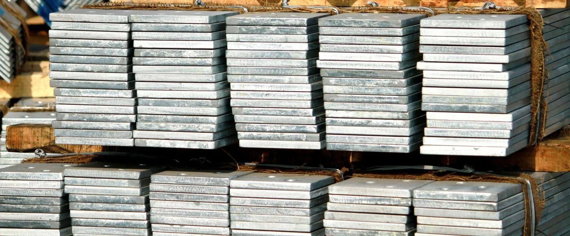 Stacks of bundled newspapers or magazines wrapped in plastic on wooden pallets in a warehouse