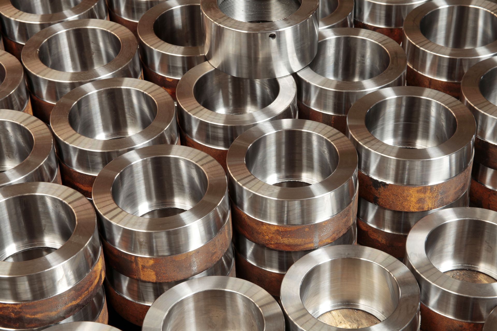 Stacks of shiny metal ring-shaped bearings or bushings arranged closely together in a workshop setting