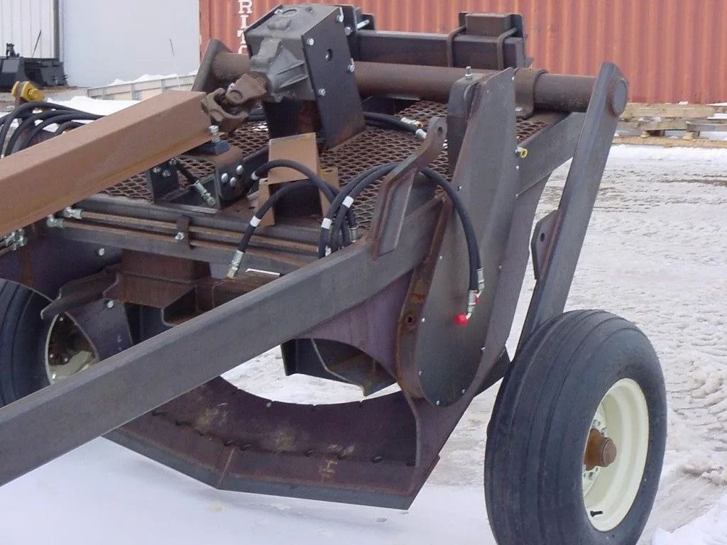 Rusty industrial machine on wheels with a large metal arm in a snowy outdoor yard