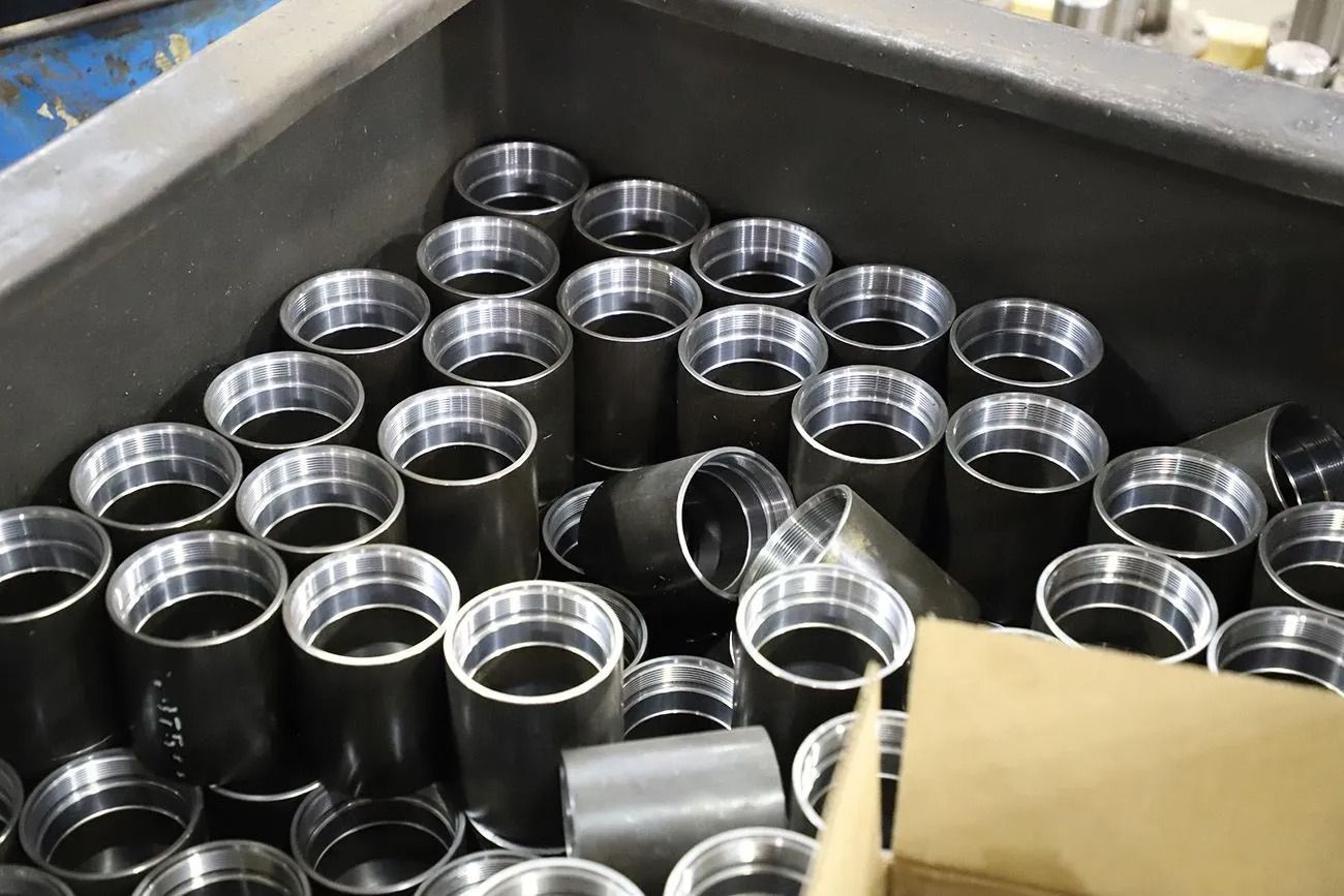 Metal cylindrical parts piled in a tray, with one tipped on its side.