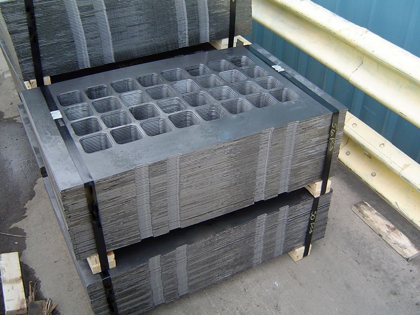 Stacked gray metal trays with mesh sides on an outdoor concrete balcony.