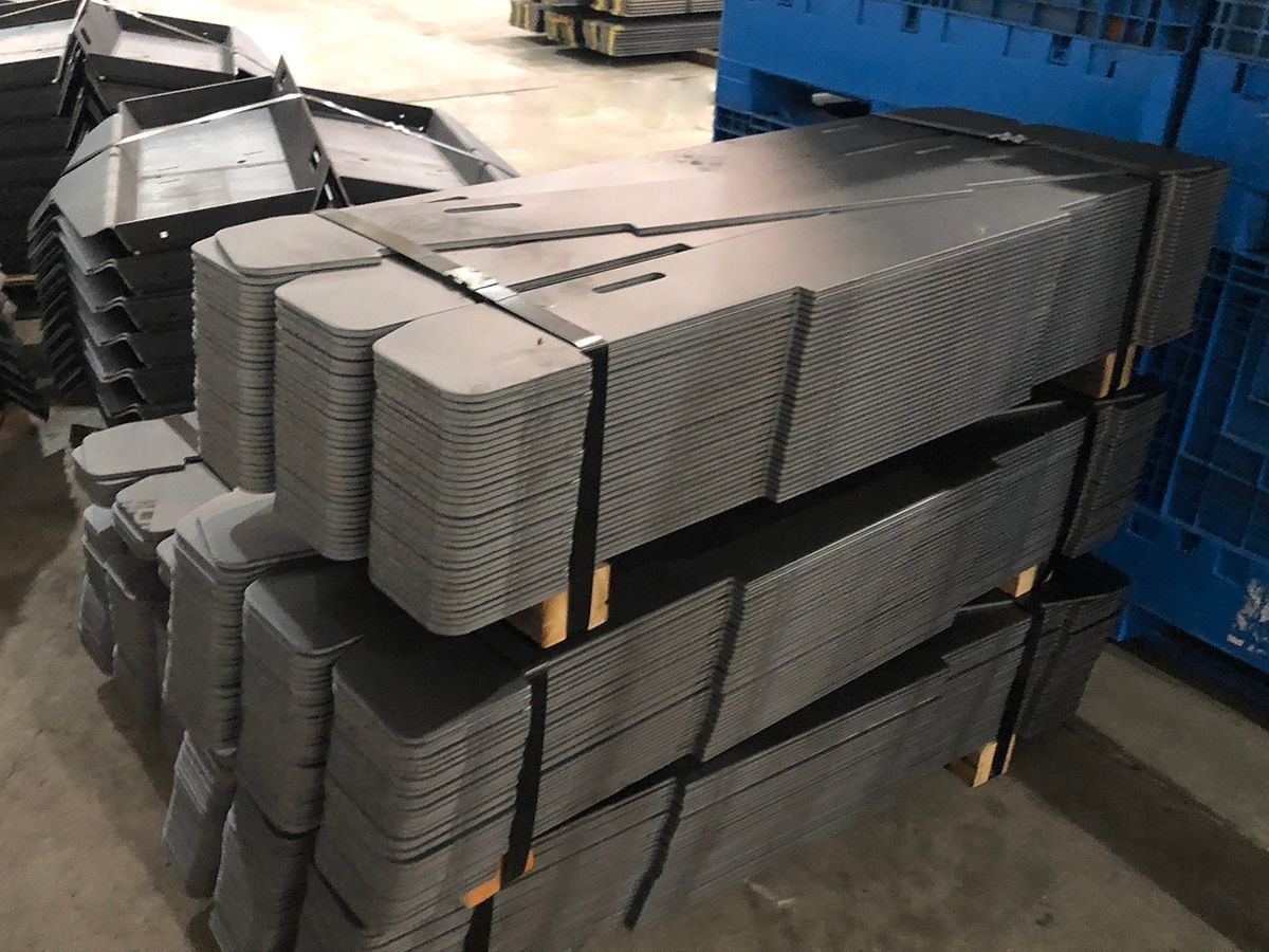 Stacks of gray plastic trays strapped on pallets in a warehouse.