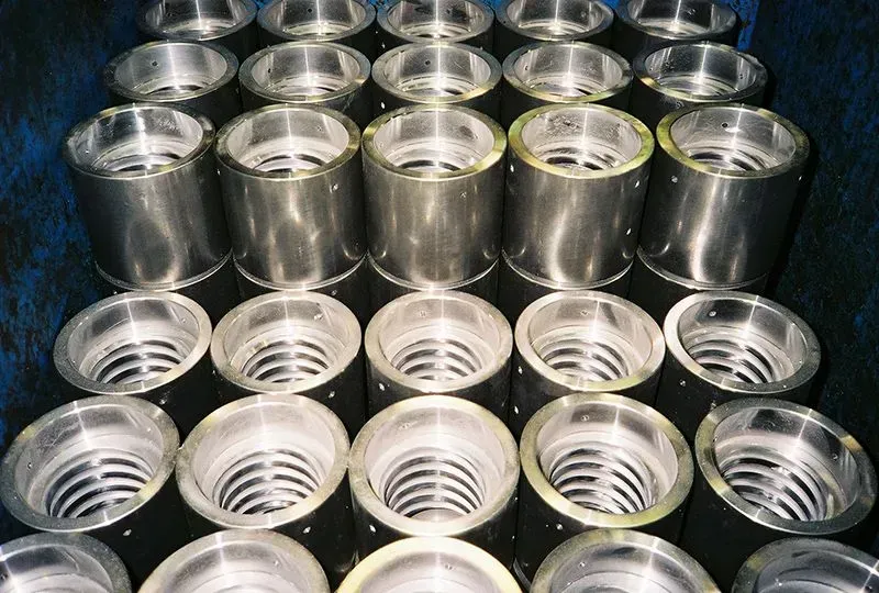 Rows of shiny metal cans viewed from above, stacked closely together on a dark surface