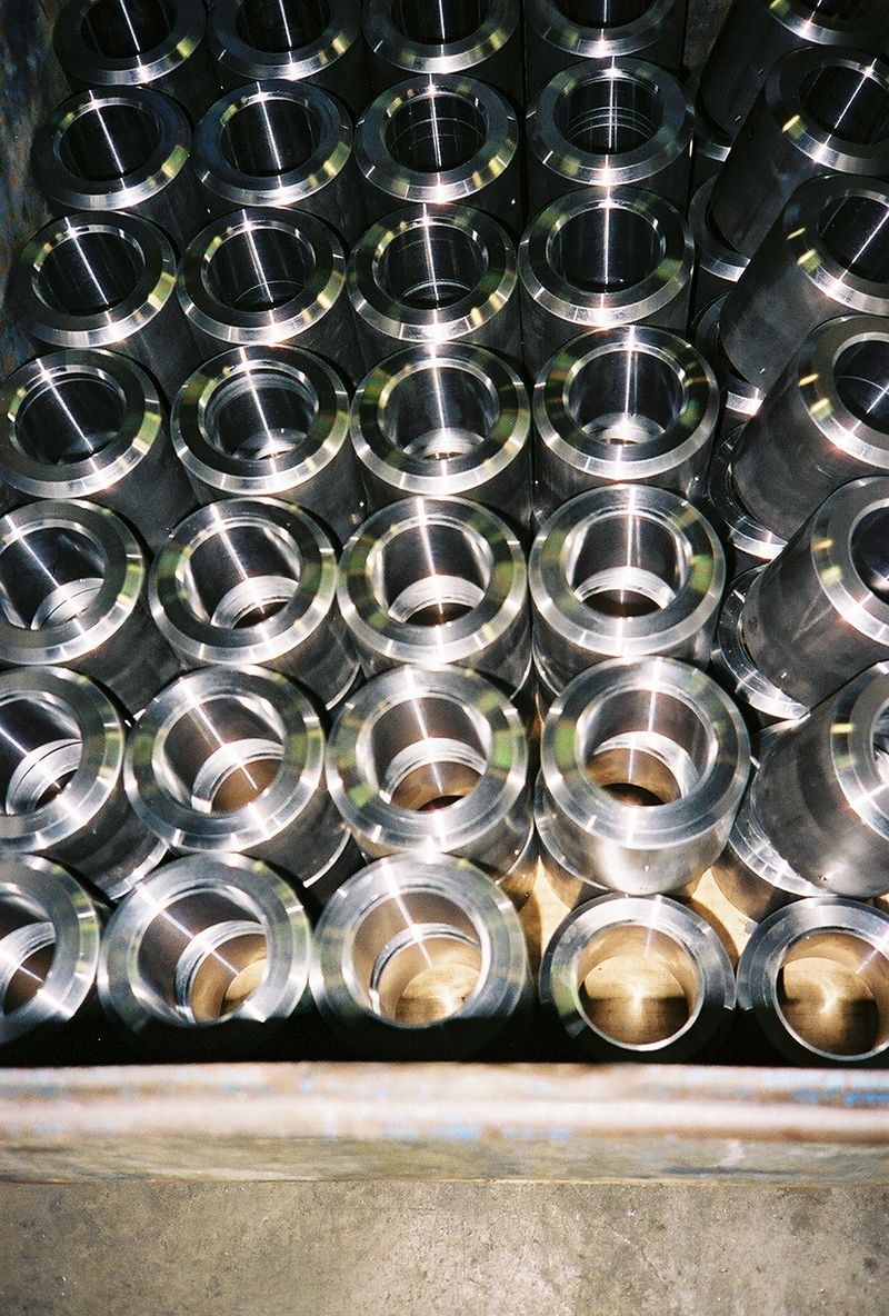 Metal cylindrical parts stacked in a storage bin, seen from above.