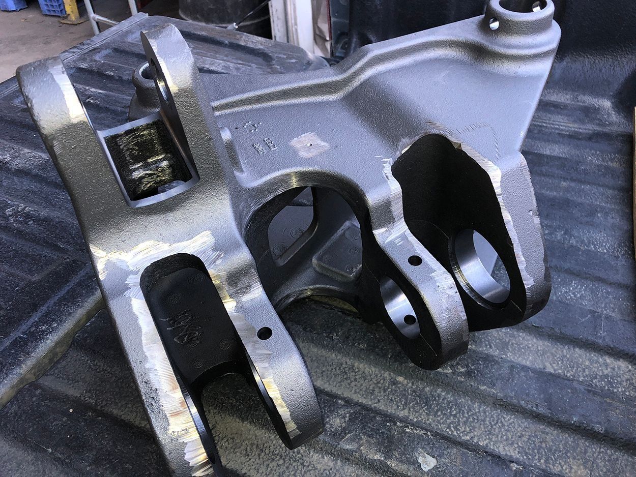 Close-up of a silver metal mechanical bracket with three forked openings on a dark surface