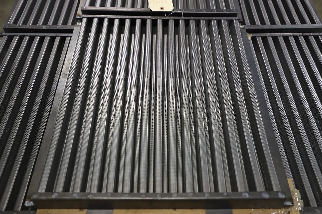 Black corrugated metal roof panel with a vent and a small beige fixture at the top.