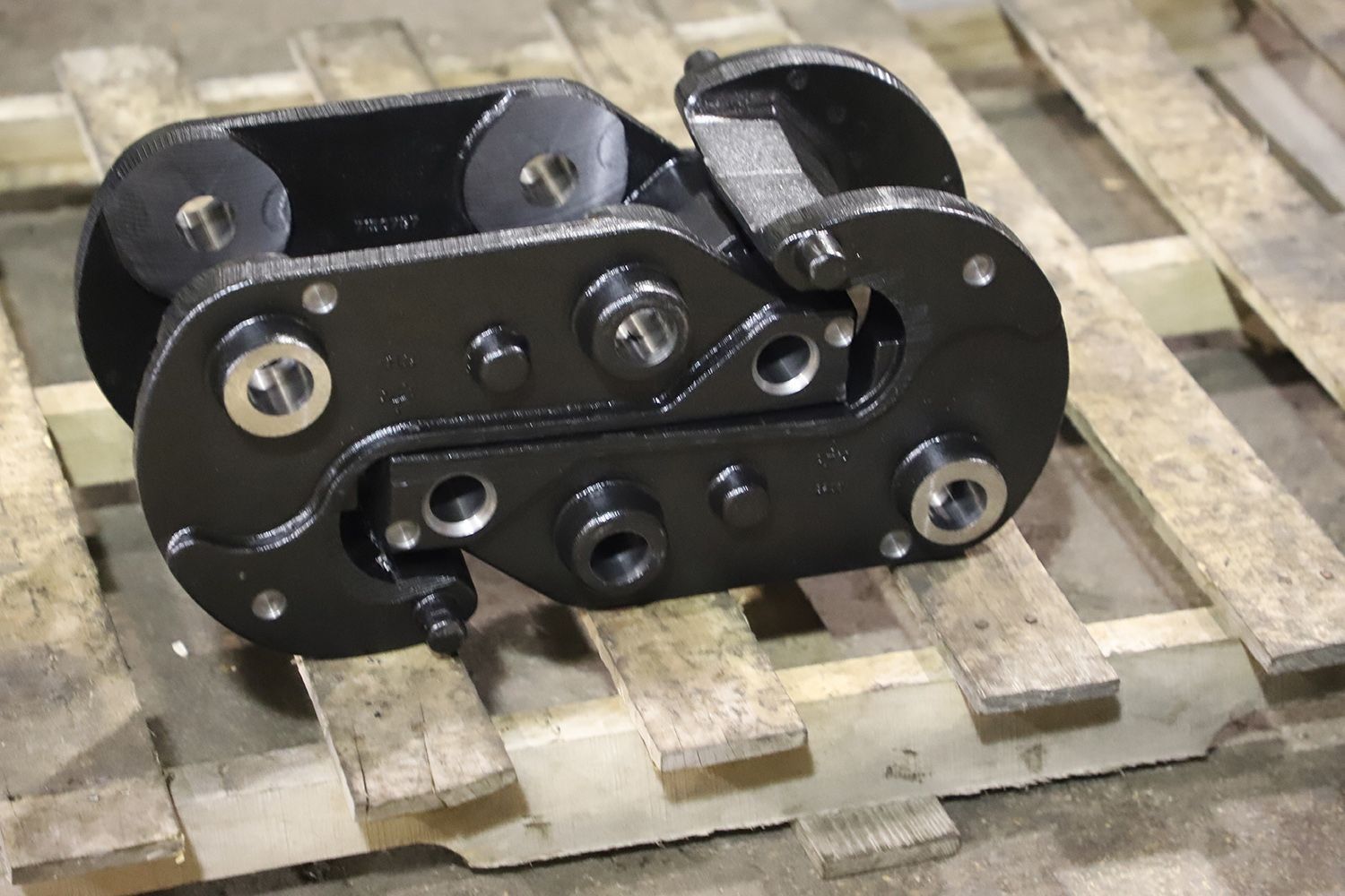 Black metal mechanical part resting on a wooden pallet