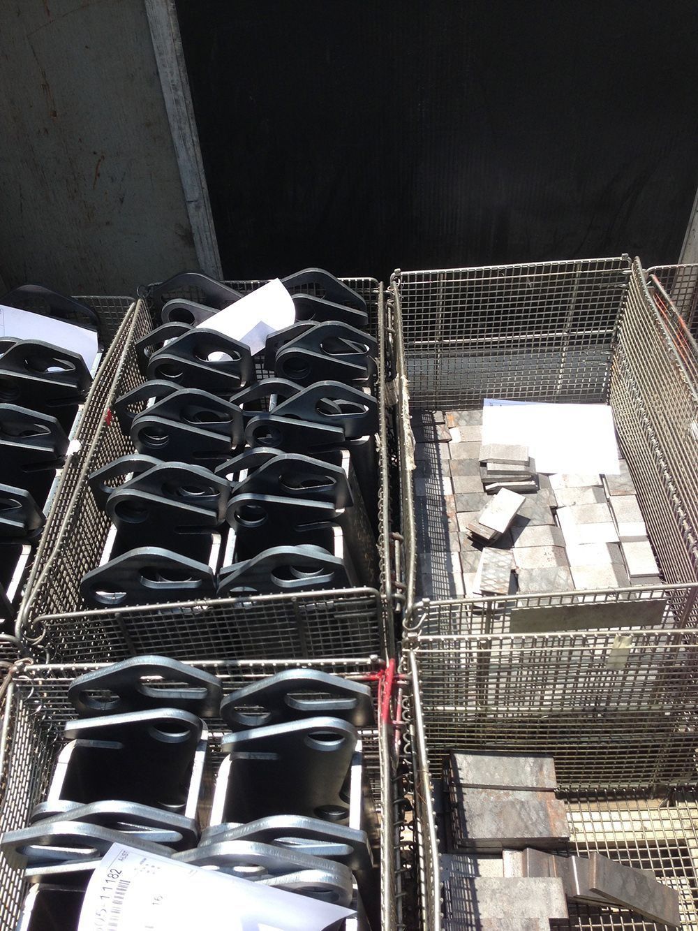 Stacked wire crates filled with black and white items in a dim indoor storage area