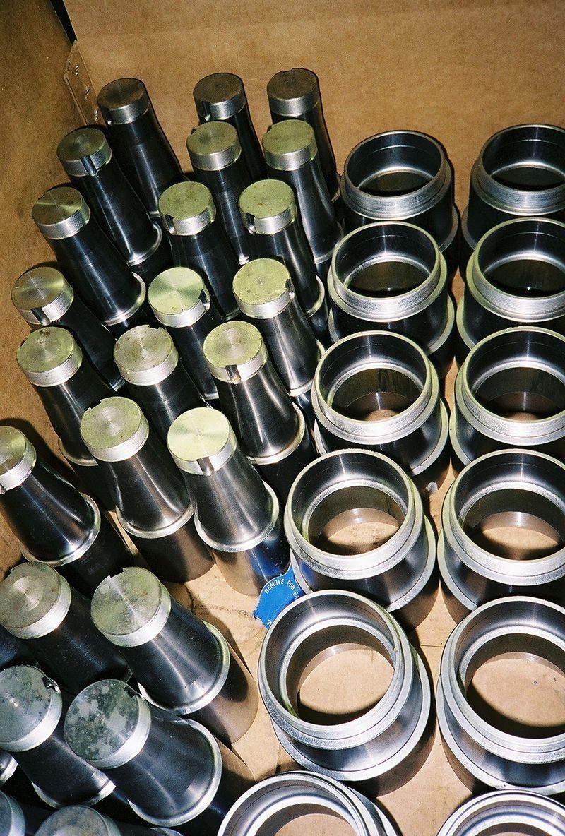 Stacked metal cylinders and rings arranged in rows on a cardboard surface.