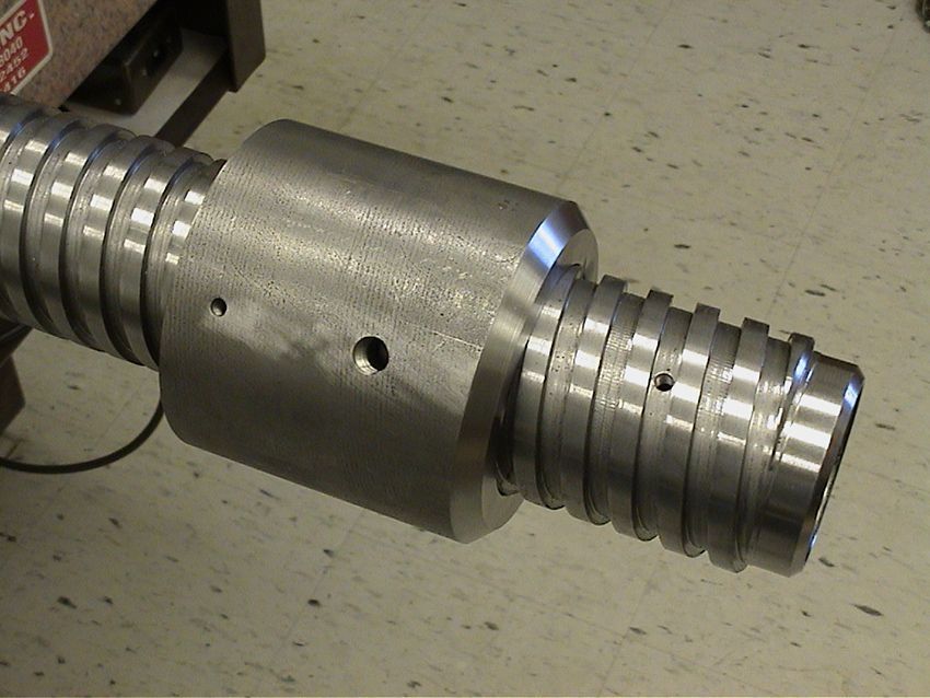 Close-up of a metal mechanical shaft with grooved ends and a central cylindrical connector.