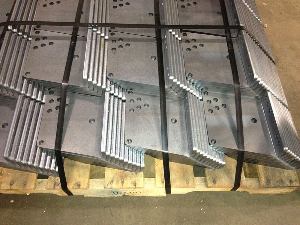 Stacks of silver corrugated metal panels leaning against a wall on a warehouse floor.
