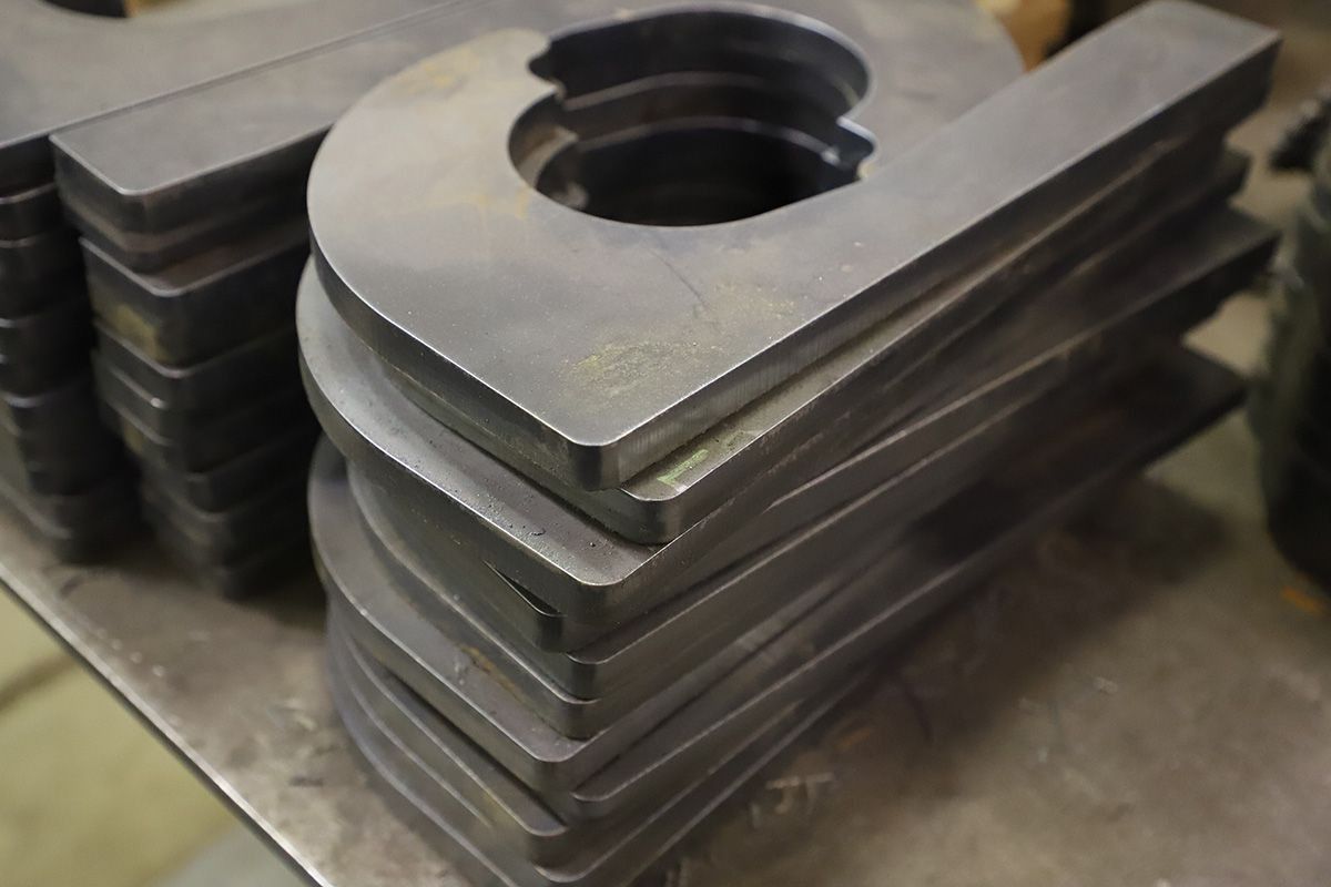 Stacked metal machine parts with a circular cutout on a workshop surface