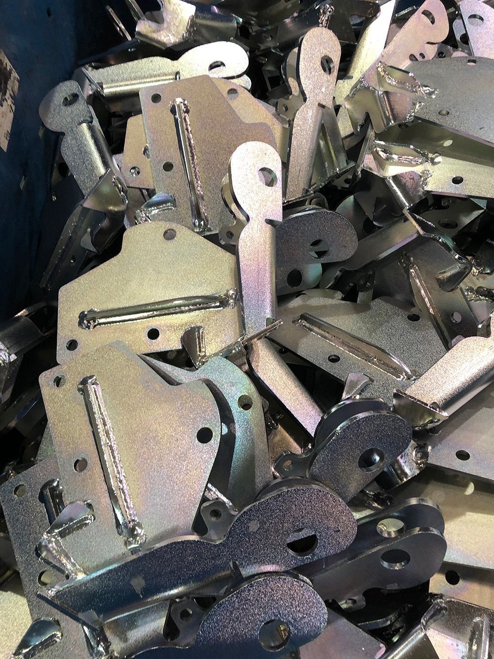 A pile of assorted metal mechanical brackets and parts in silver and dark gray.
