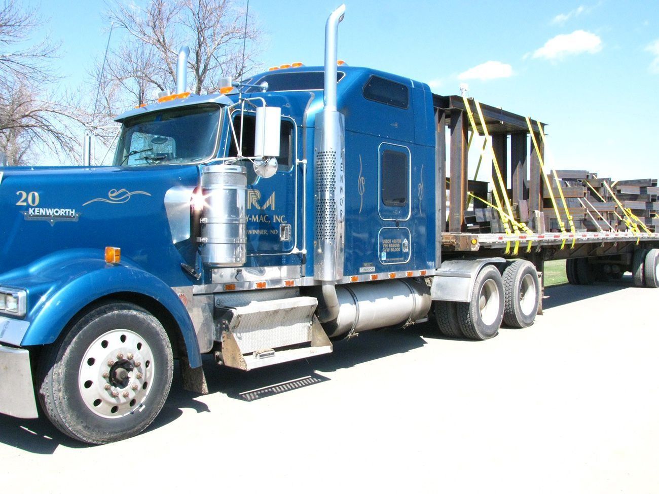 Blue semi truck hauling a car trailer on a snowy road