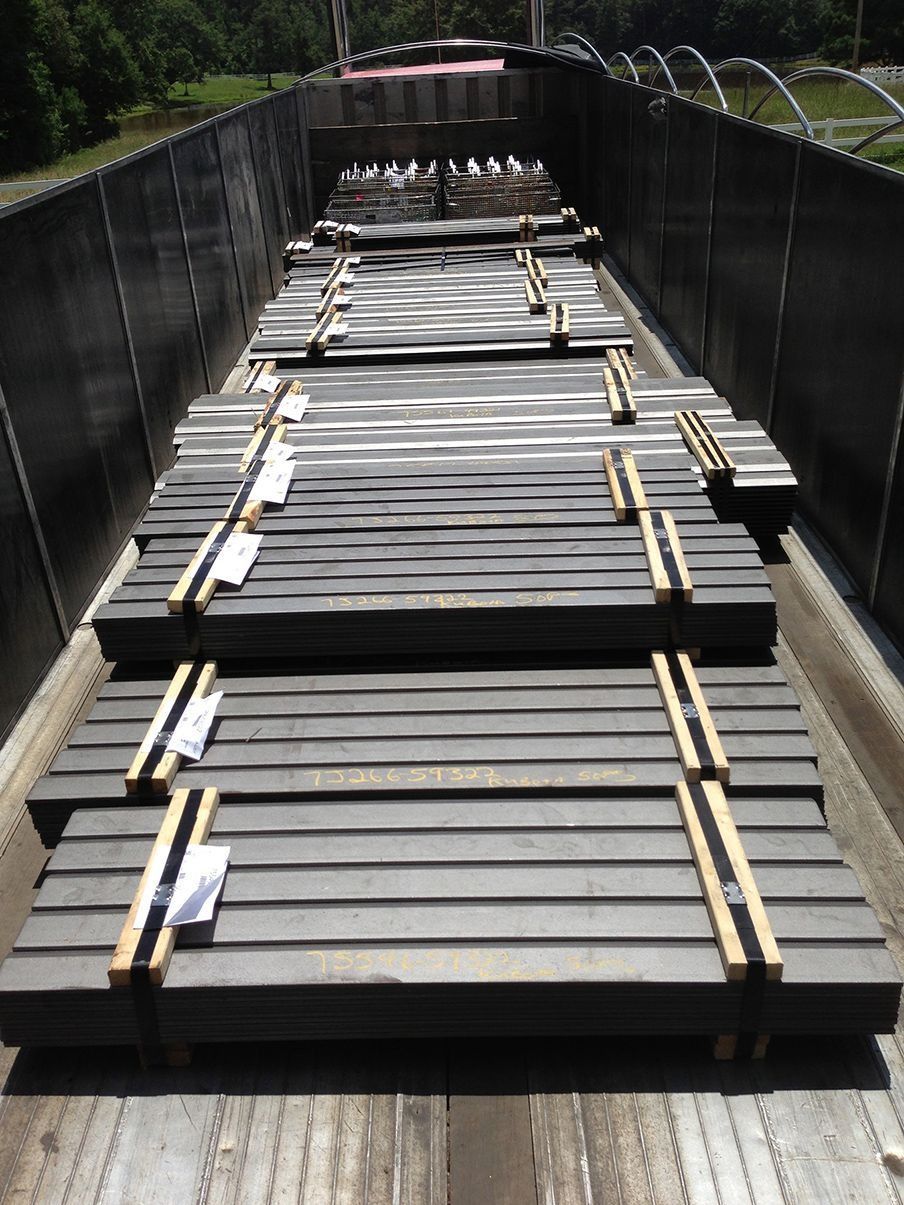 Stacked wooden planks secured by straps on a narrow bridge walkway outdoors.