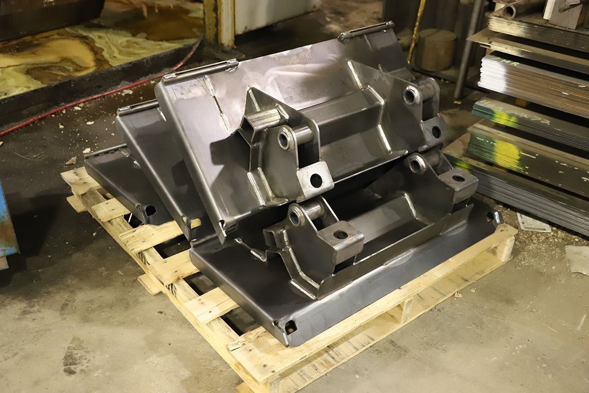 Metal industrial machine part mounted on a wooden pallet in a warehouse setting