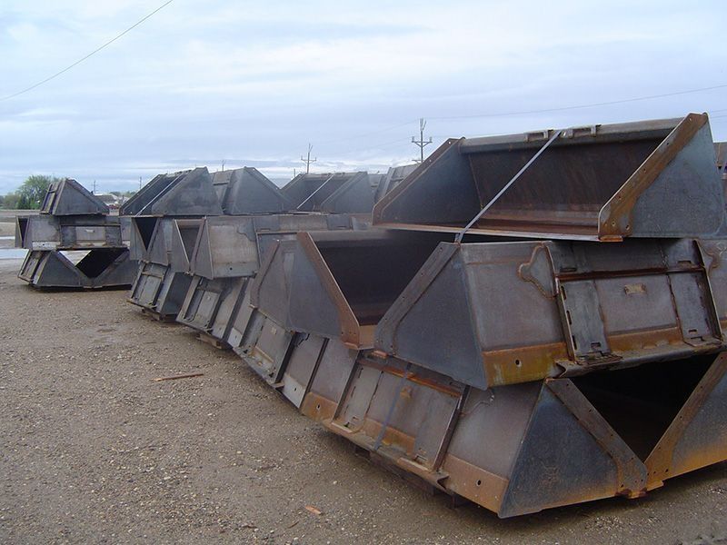 Stacked rusty metal scrap bins in an outdoor yard under a cloudy sky