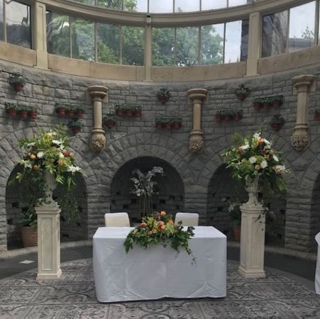 Wedding table with white cloth and floral arrangements in a stone indoor courtyard