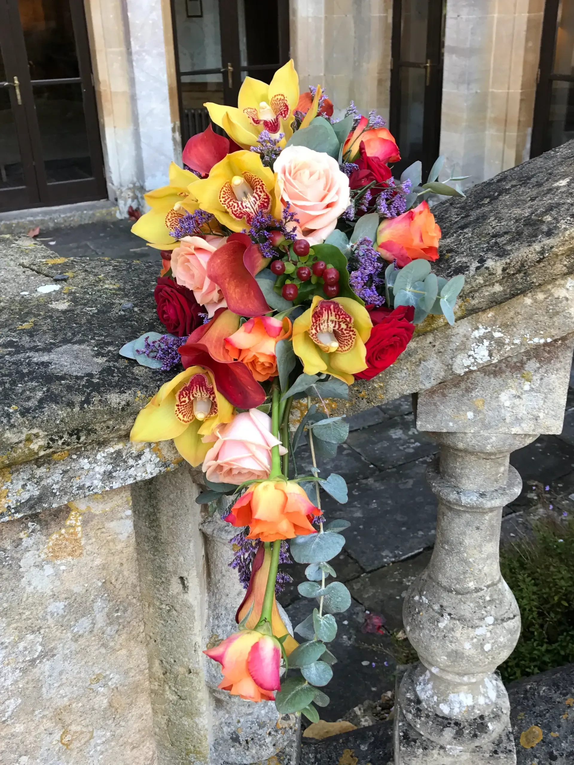 Bouquet of peach, yellow, and red roses on a stone balustrade outdoors