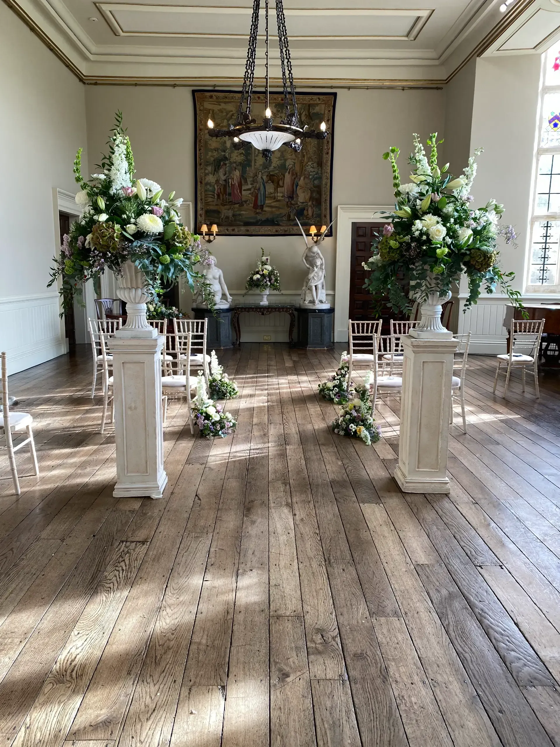 Decorated ballroom aisle with white pedestals, floral arrangements, and candles for a formal event