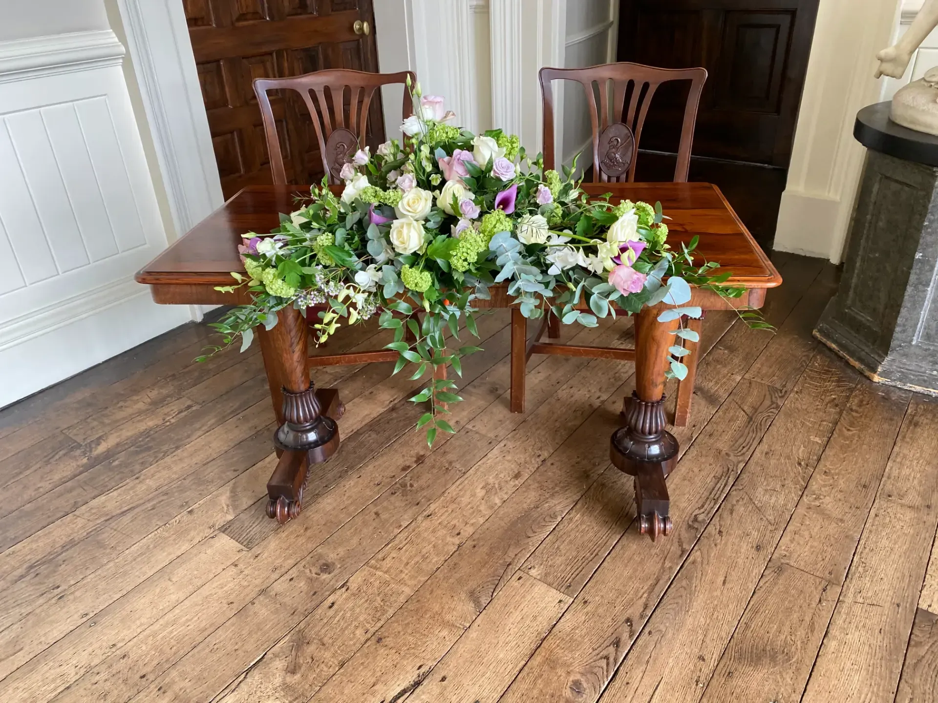 Wooden dining table with a lush floral centerpiece in a room with hardwood floors