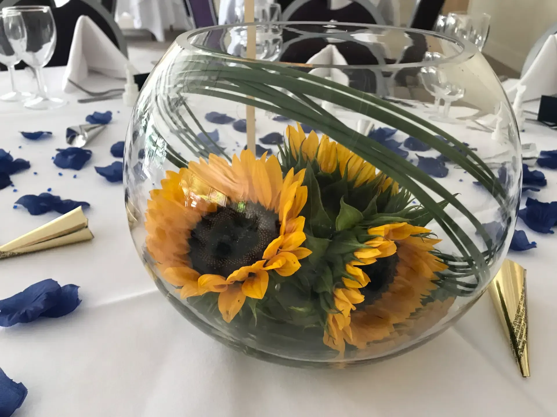 Sunflowers arranged in a glass bowl centerpiece on a decorated dining table