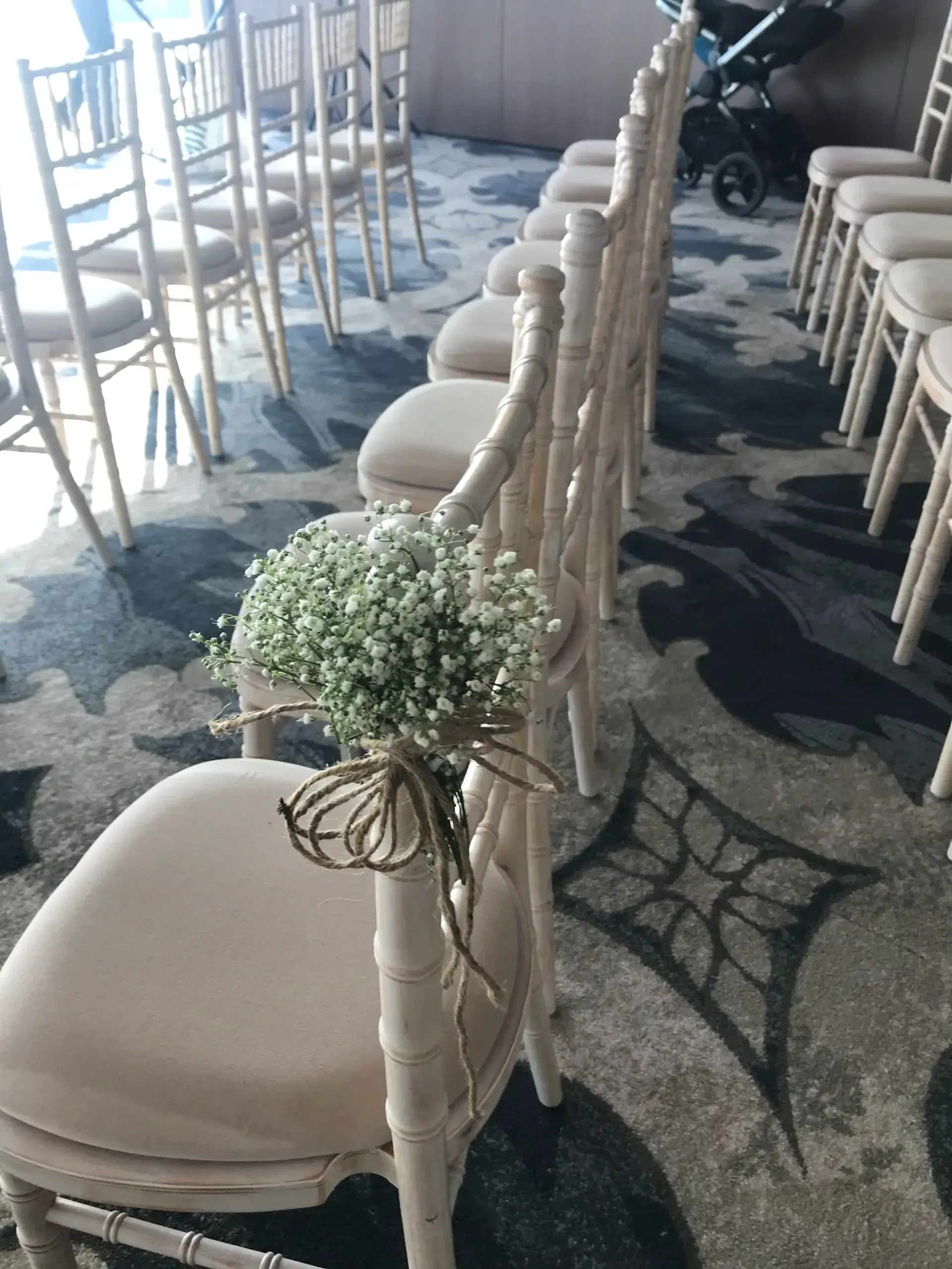 Beige chairs lined along a rope barrier with greenery on a patterned outdoor floor