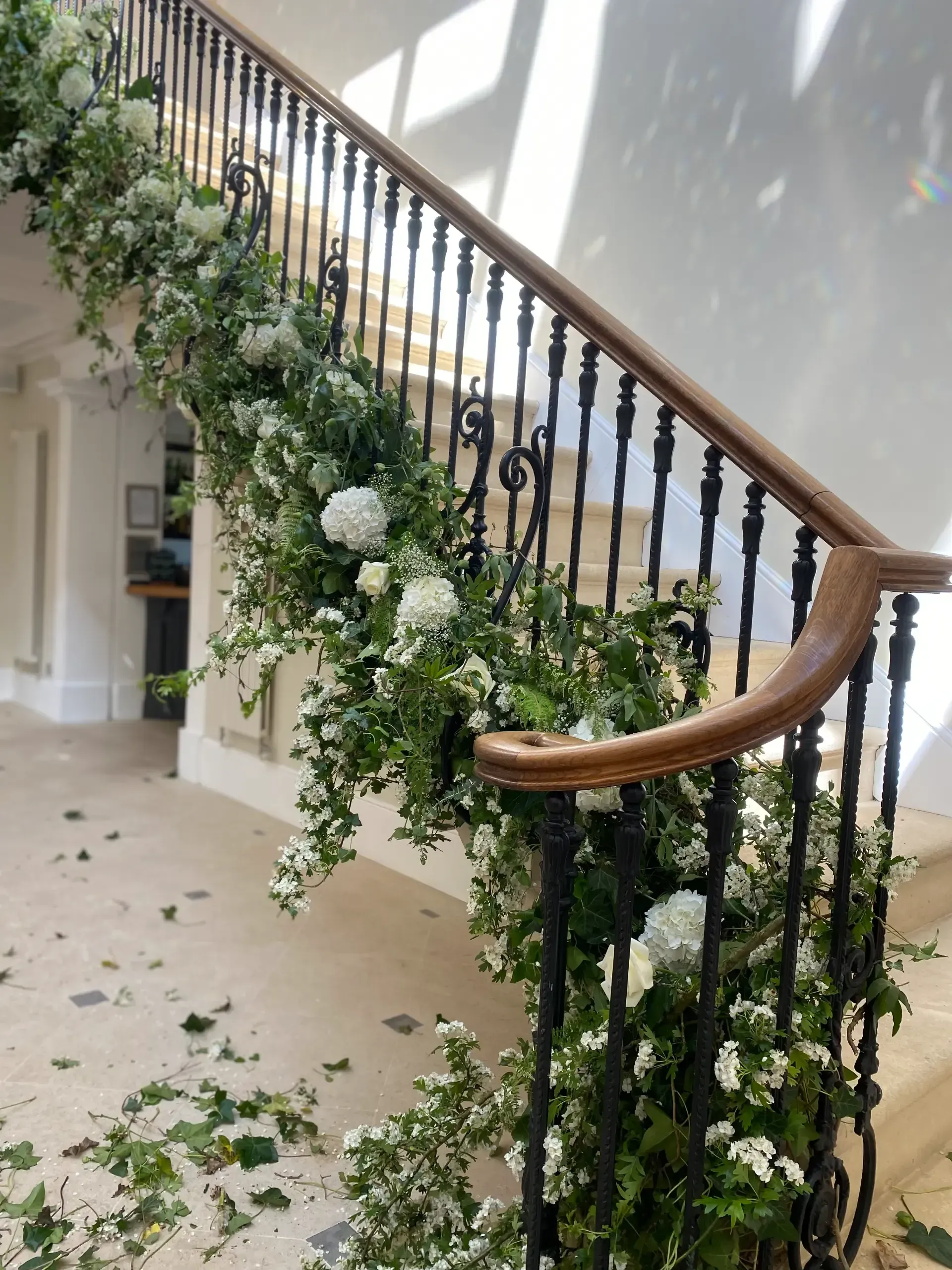 Flower-covered staircase with white floral garland and scattered greenery on the floor