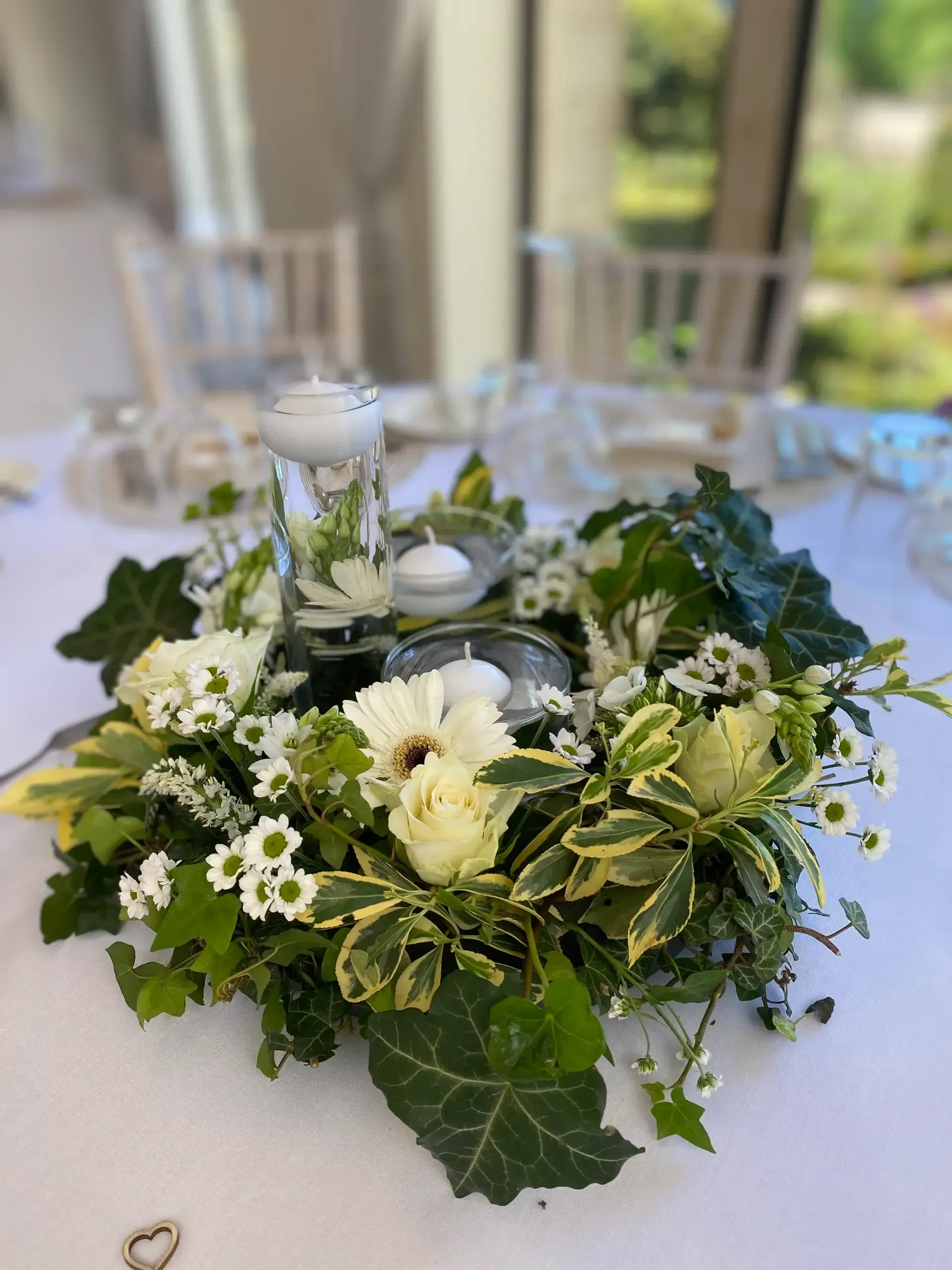 White floral centerpiece with candles and greenery on a table