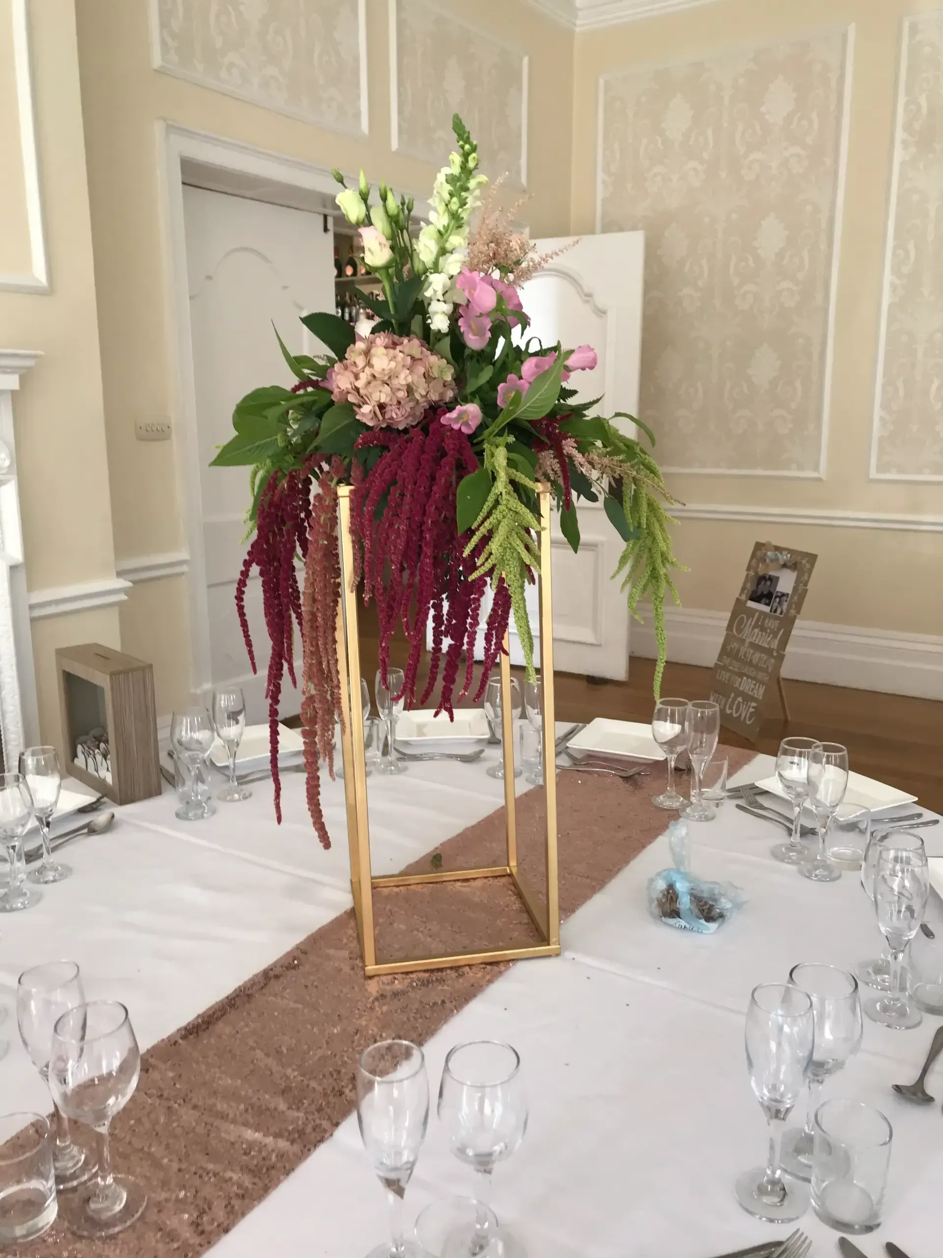 Elegant banquet table with a tall burgundy and cream floral centerpiece in a formal room