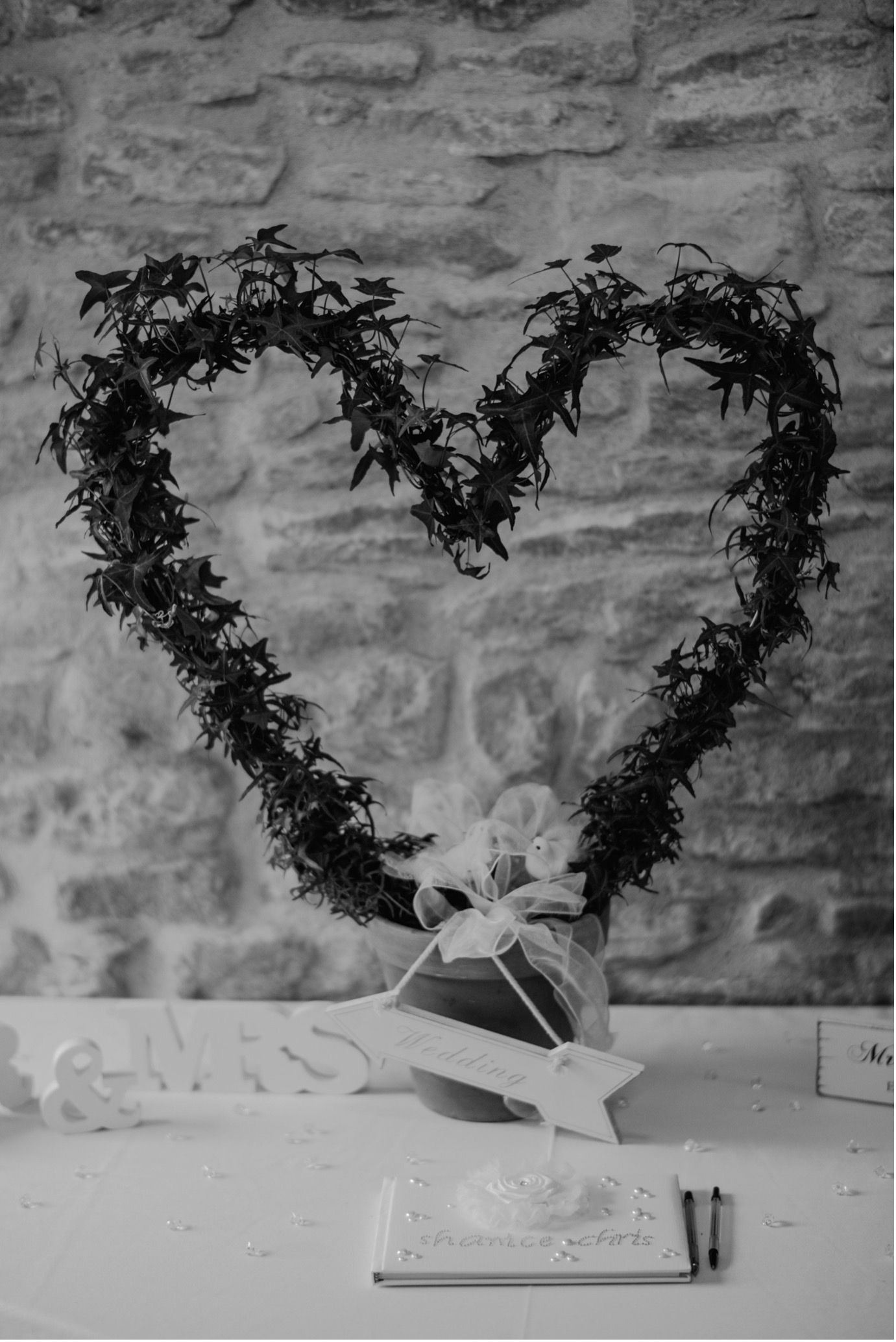Heart-shaped wreath on a stone wall above a table with a small decorative object.
