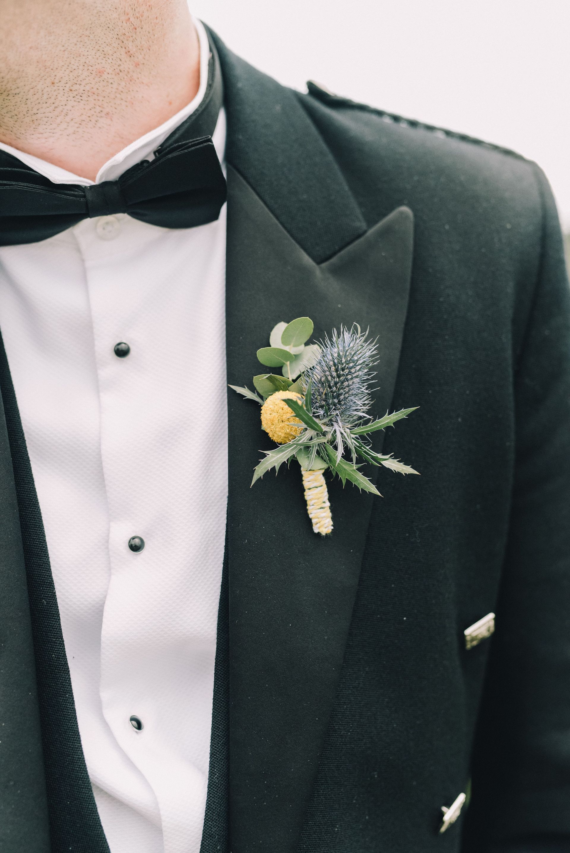 Black tuxedo with white shirt, bow tie, and boutonniere on a formal suit jacket.