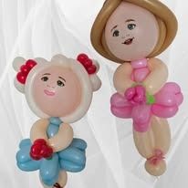 Two balloon figures with smiling faces, one in blue with red bows and one in pink with a tan hat.