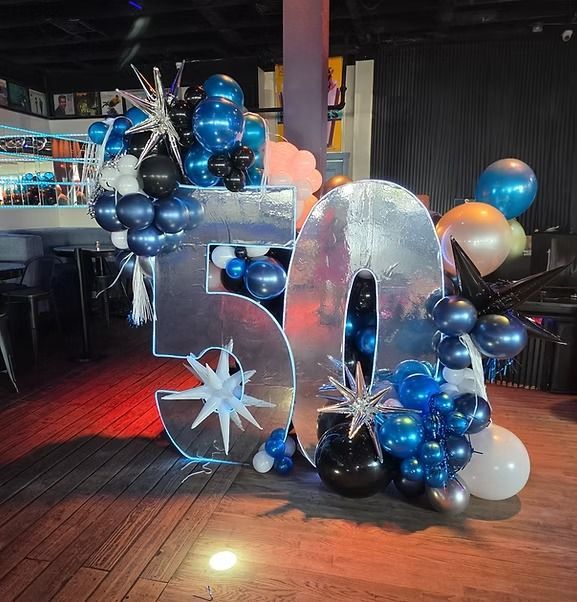Blue and silver 50th birthday balloon display with large “50” numbers and star accents