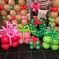 Balloon display of colorful flower and gift shapes against a wall of tan and red balloons
