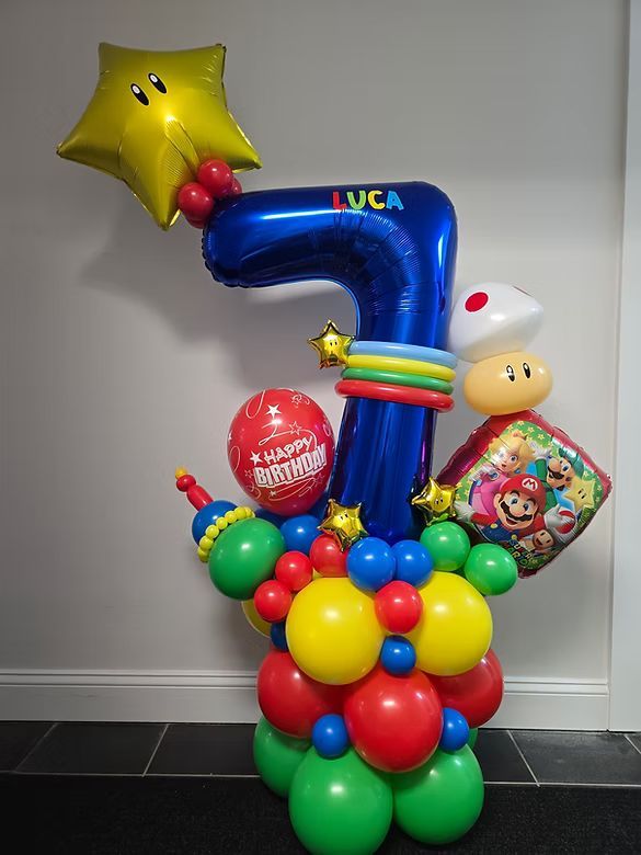 Colorful balloon arrangement with a blue number 7, star, and decorative balloons on a wall background