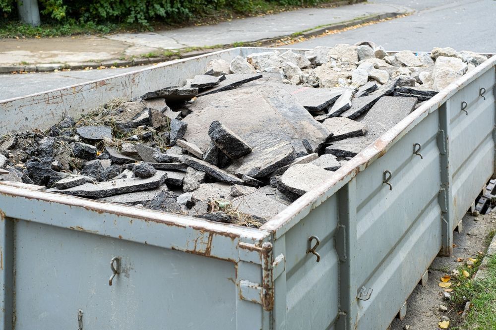 A Dumpster Filled With Rocks And Dirt Is Sitting On The Side Of The Road — Tuscany Concreting In Airlie Beach, QLD