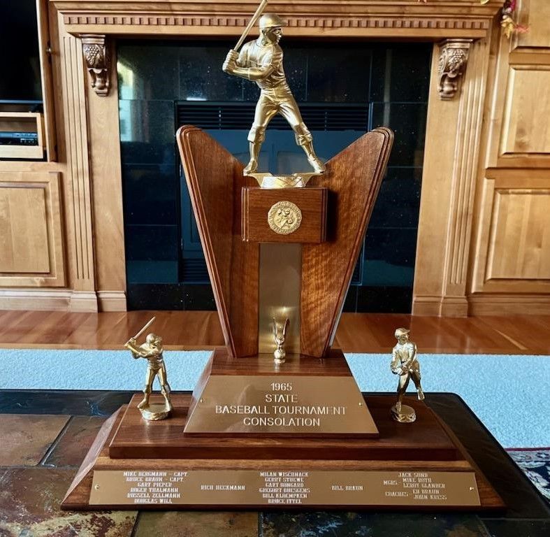A wooden baseball trophy with three gold-colored figures and a central plaque reading 