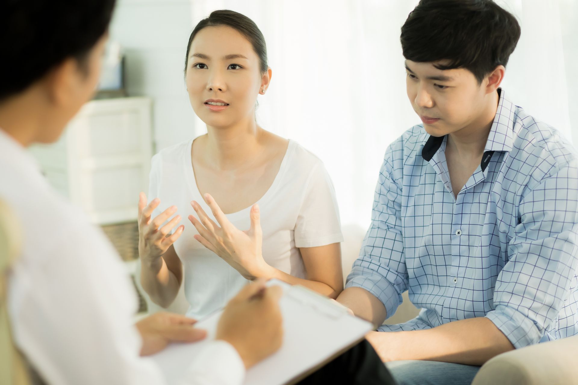 A man and a woman are sitting on a couch talking to a doctor.