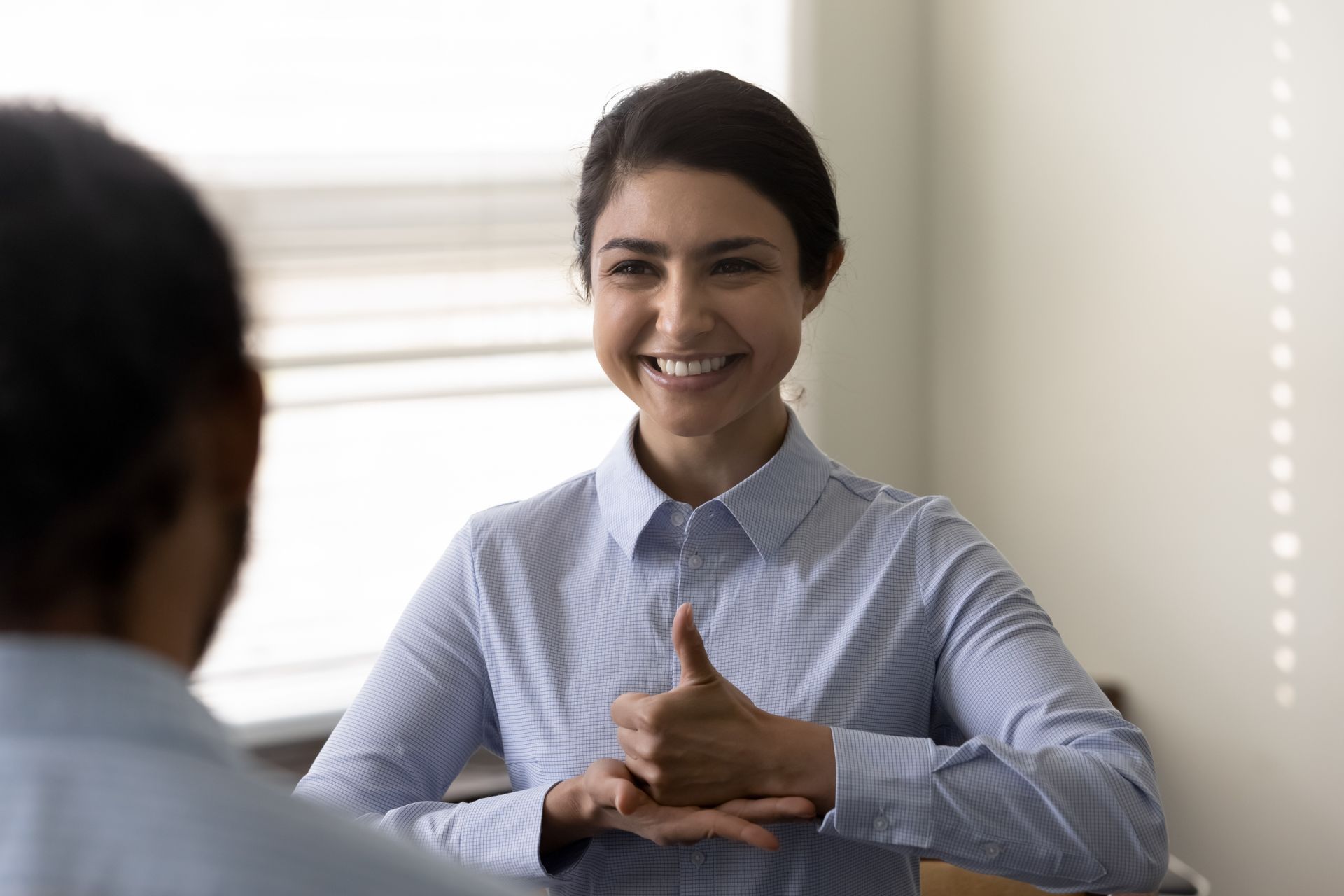 A woman is giving a thumbs up during a job interview.