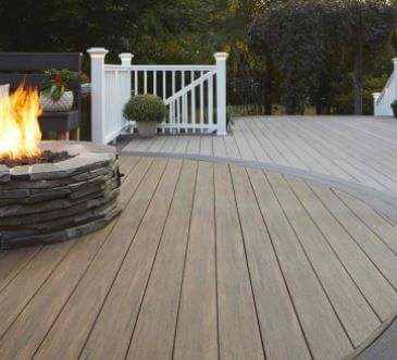 Modern backyard deck with fire pit, white railing, and curved wooden flooring