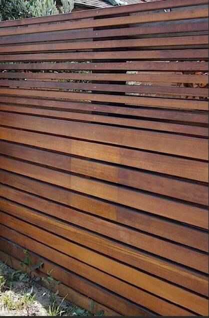 Horizontal wooden slat fence in brown tones with small gaps showing through.