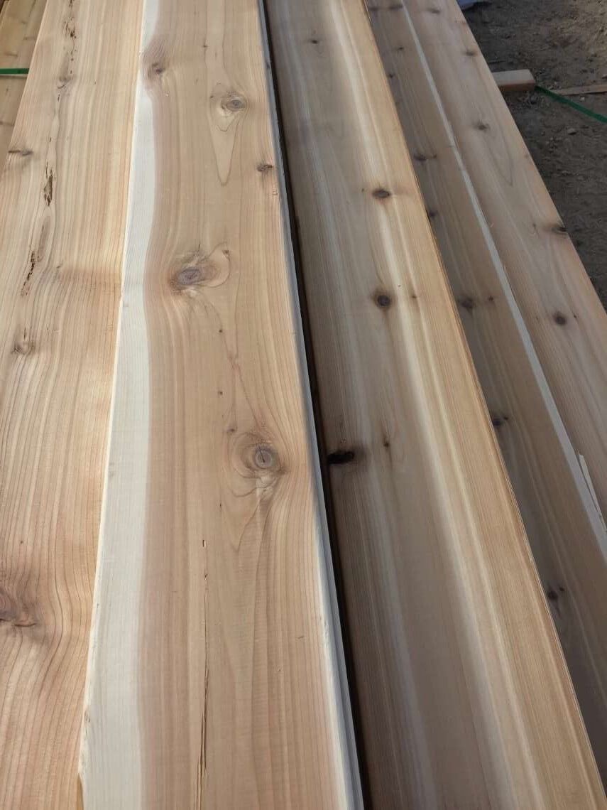 Stacked light-colored wooden planks with visible knots and a narrow gap between boards
