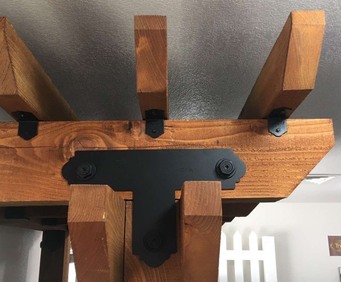 Close-up of a wooden slatted structure with black metal brackets against a ceiling background