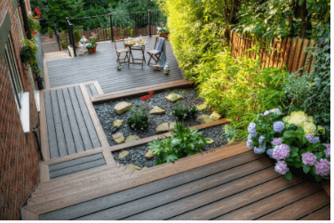 Wooden backyard deck with seating and a small garden path beside flowering plants