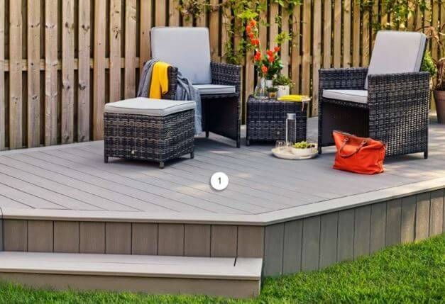 Wicker patio seating set on a wooden deck with gray cushions, a small table, and an orange bag