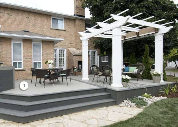 Backyard patio with pergola, outdoor dining set, and steps beside a brick house