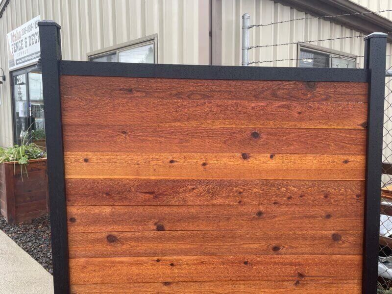 Wooden privacy fence with dark posts and horizontal stained boards in an outdoor yard.
