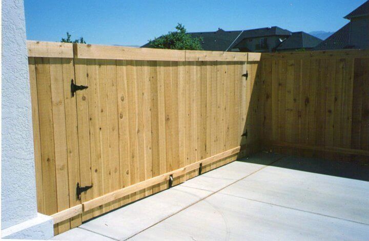 Wooden privacy fence enclosing a concrete patio under bright sunlight